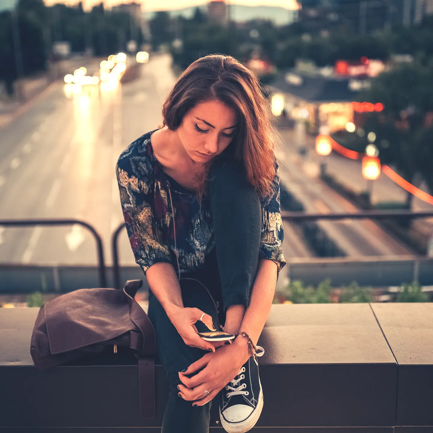 Eine Jugendliche schaut nachdenklich auf ihr Handy.