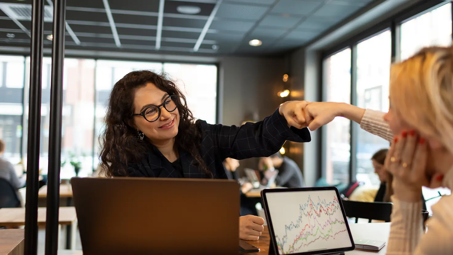 Zwei Frauen im Büro begrüßen sich mit Fäusten