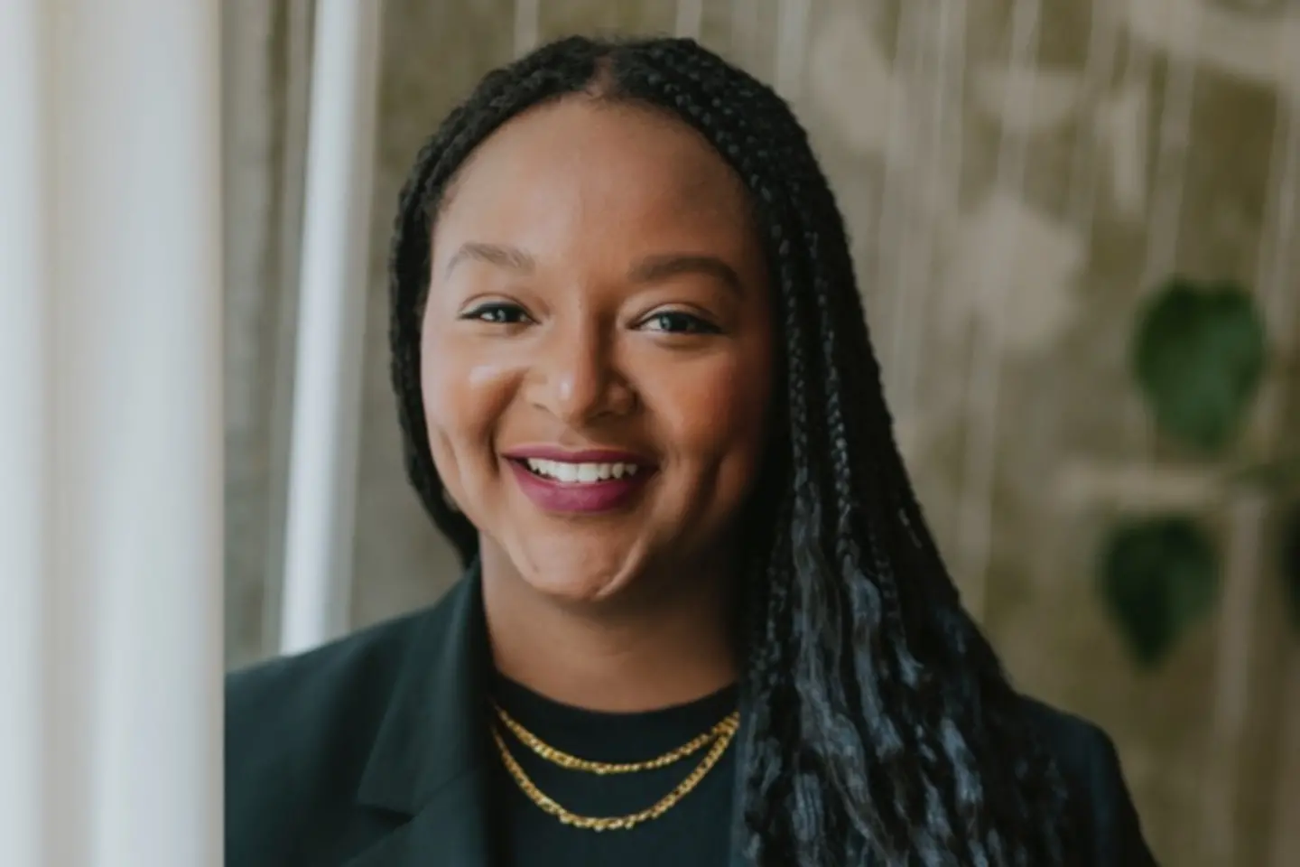 eine dunkelhäutige Frau mit langem schwarzem Haar lächelt in die Kamera 