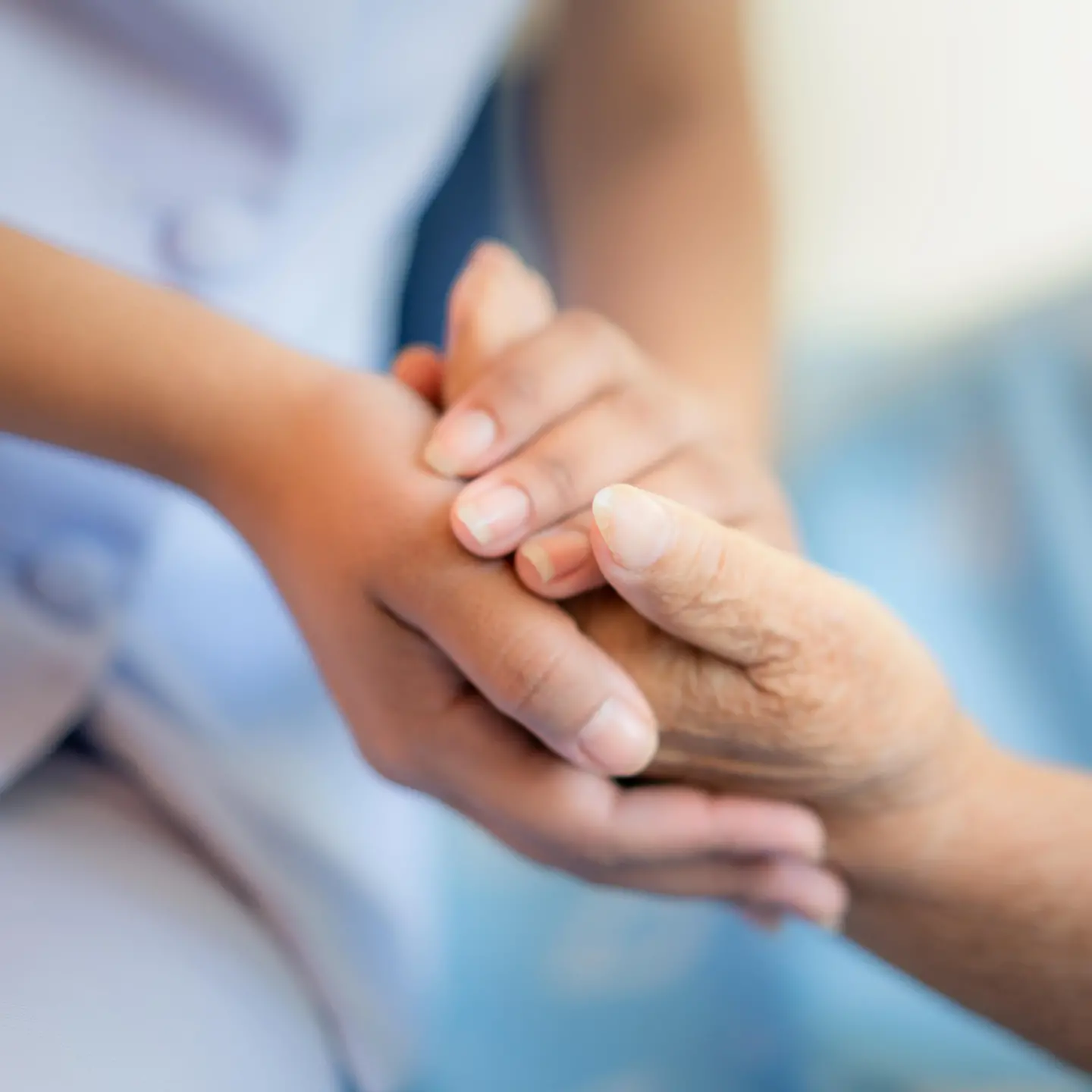 Pflegerin hält die Hand einer älteren Frau