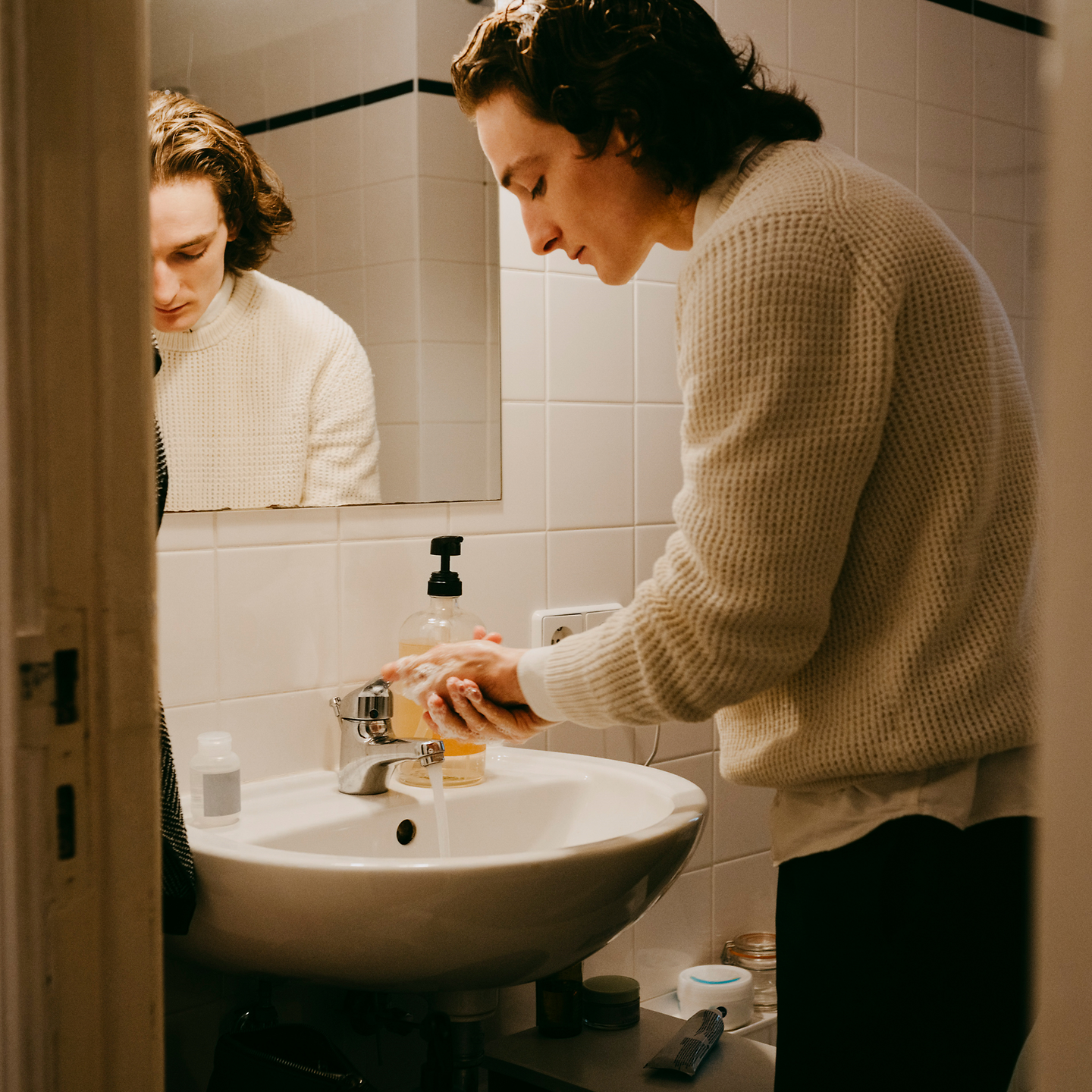 Ein junger Mann wäscht sich im Bad die Hände