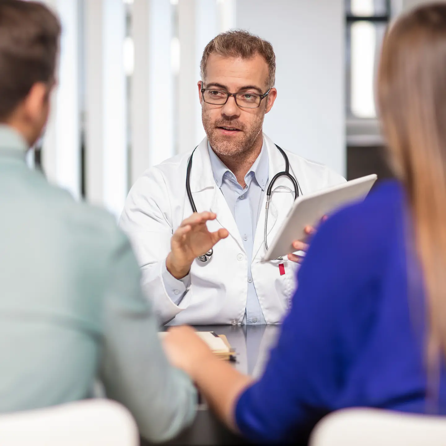 Ein Arzt berät ein Paar an einem Schreibtisch