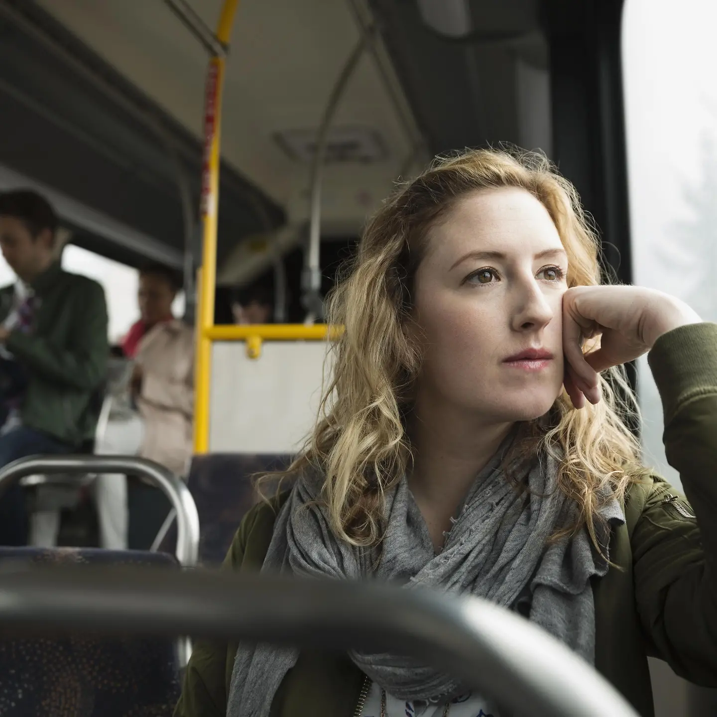 Eine junge Frau im Bus schaut besorgt aus dem Fenster