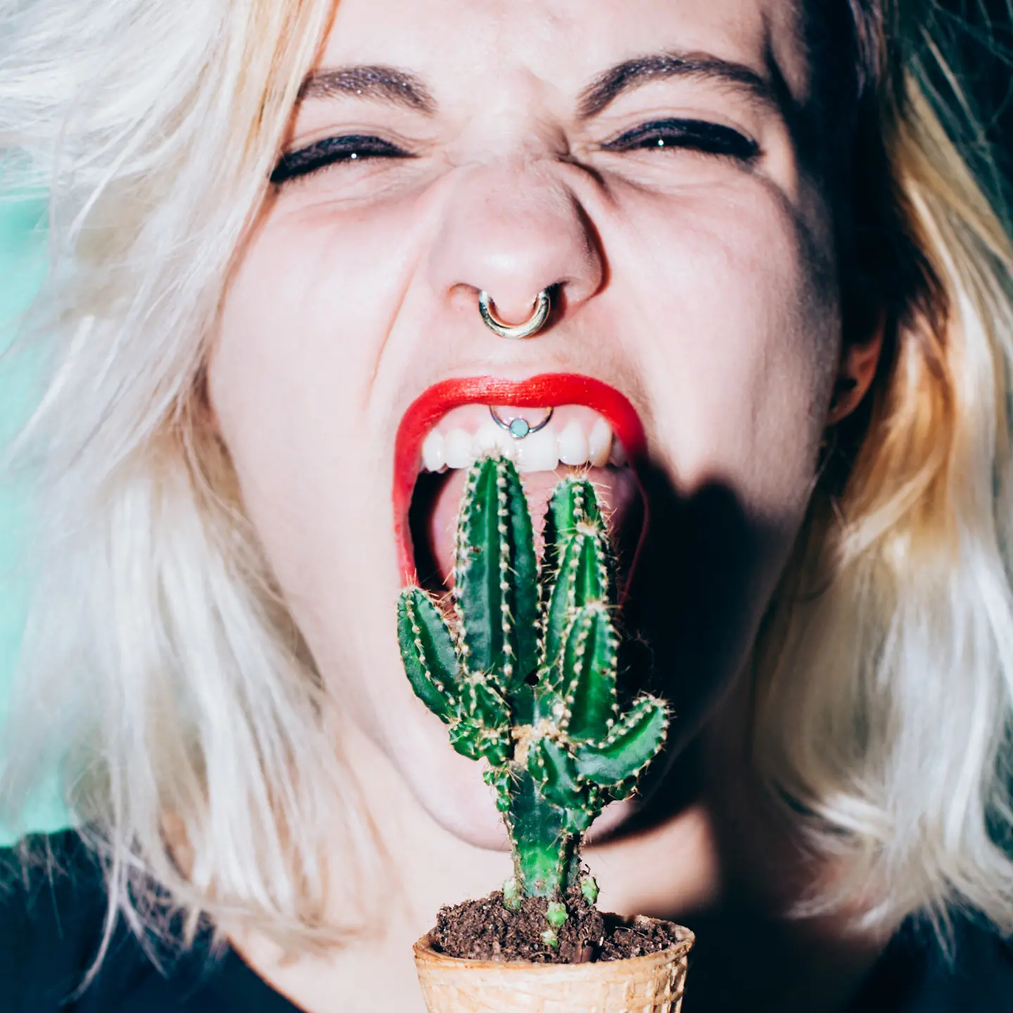 Eine junge Frau beißt in einen Kaktus