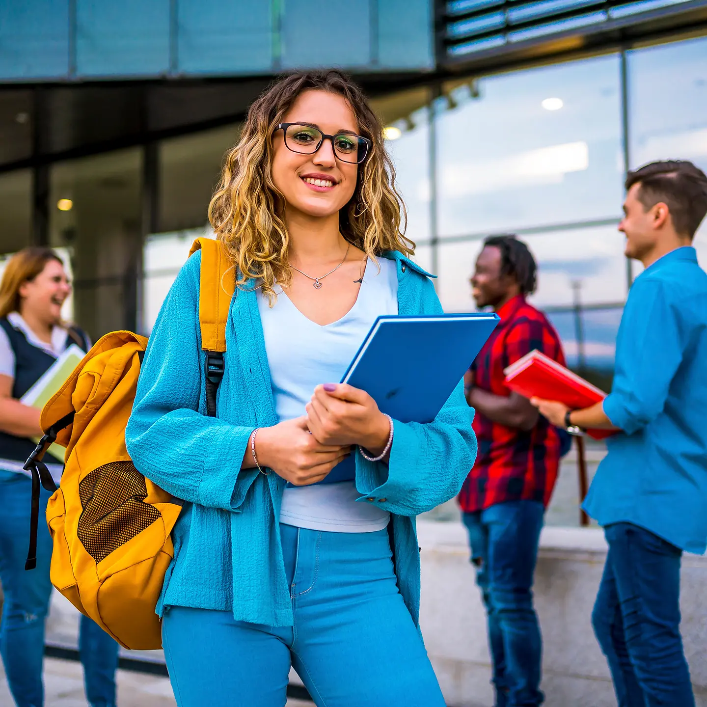 Smiling collage student standing with her colleagues in background
