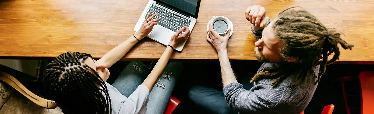 A young man and a woman with a laptop sitting in a café