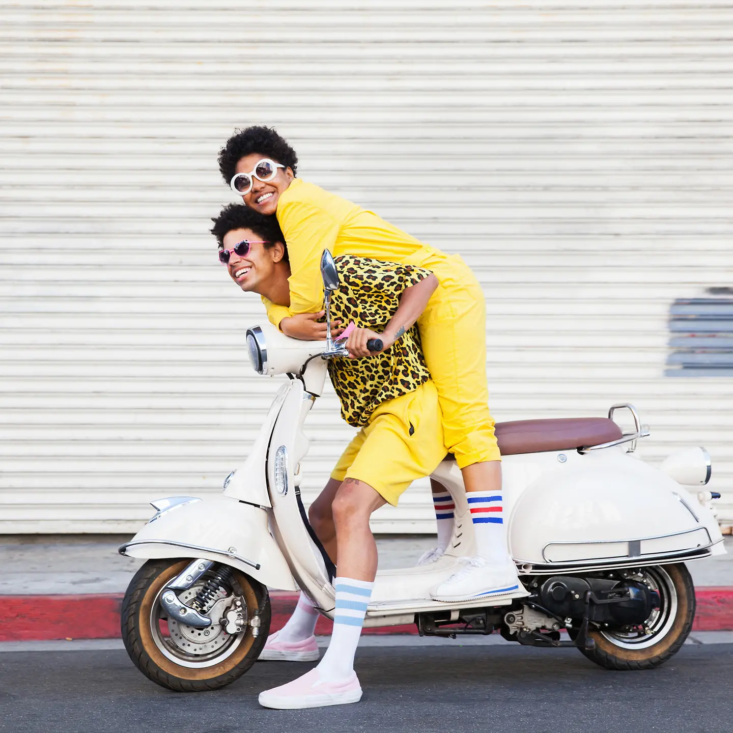 Zwei junge Menschen sitzen im Urlaub auf einem Motorrad.