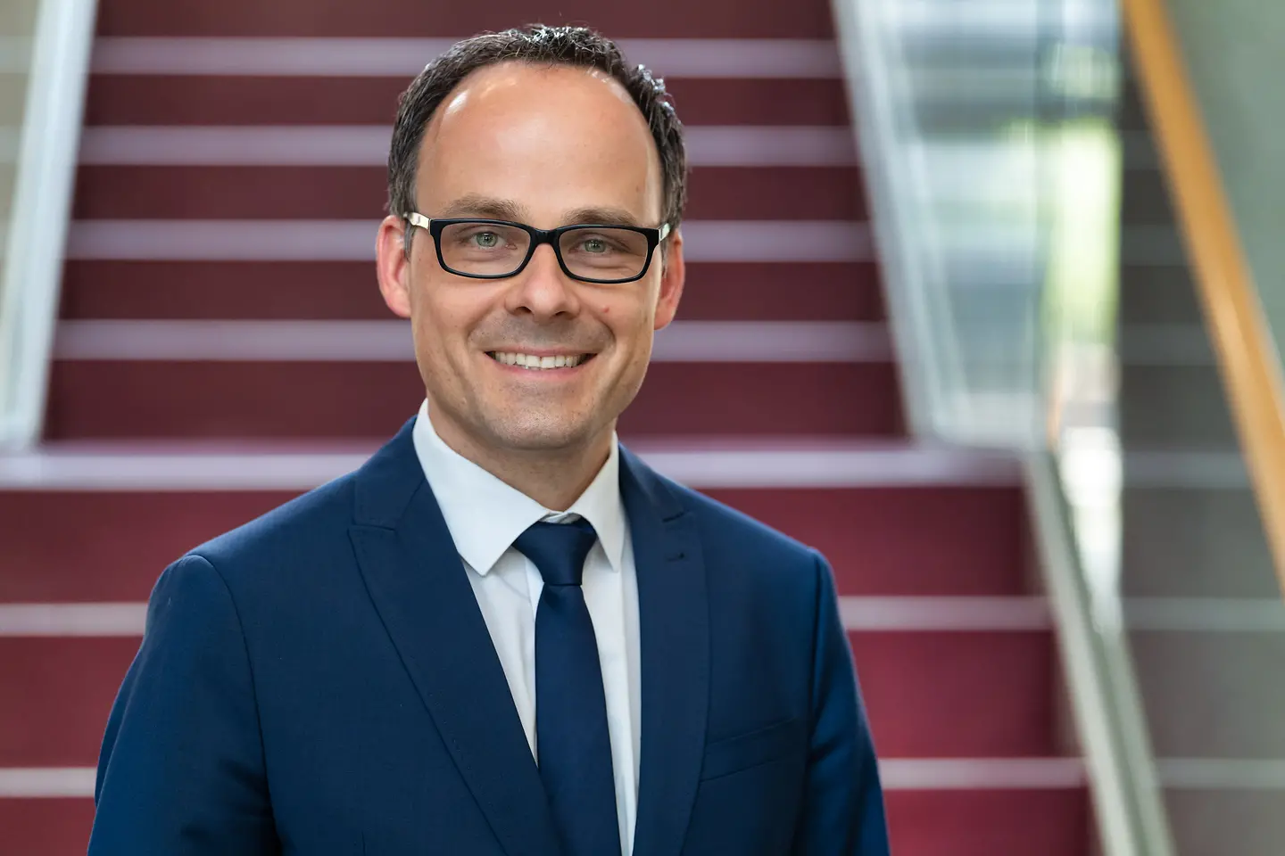 Dennis Alt steht vor einer Treppe