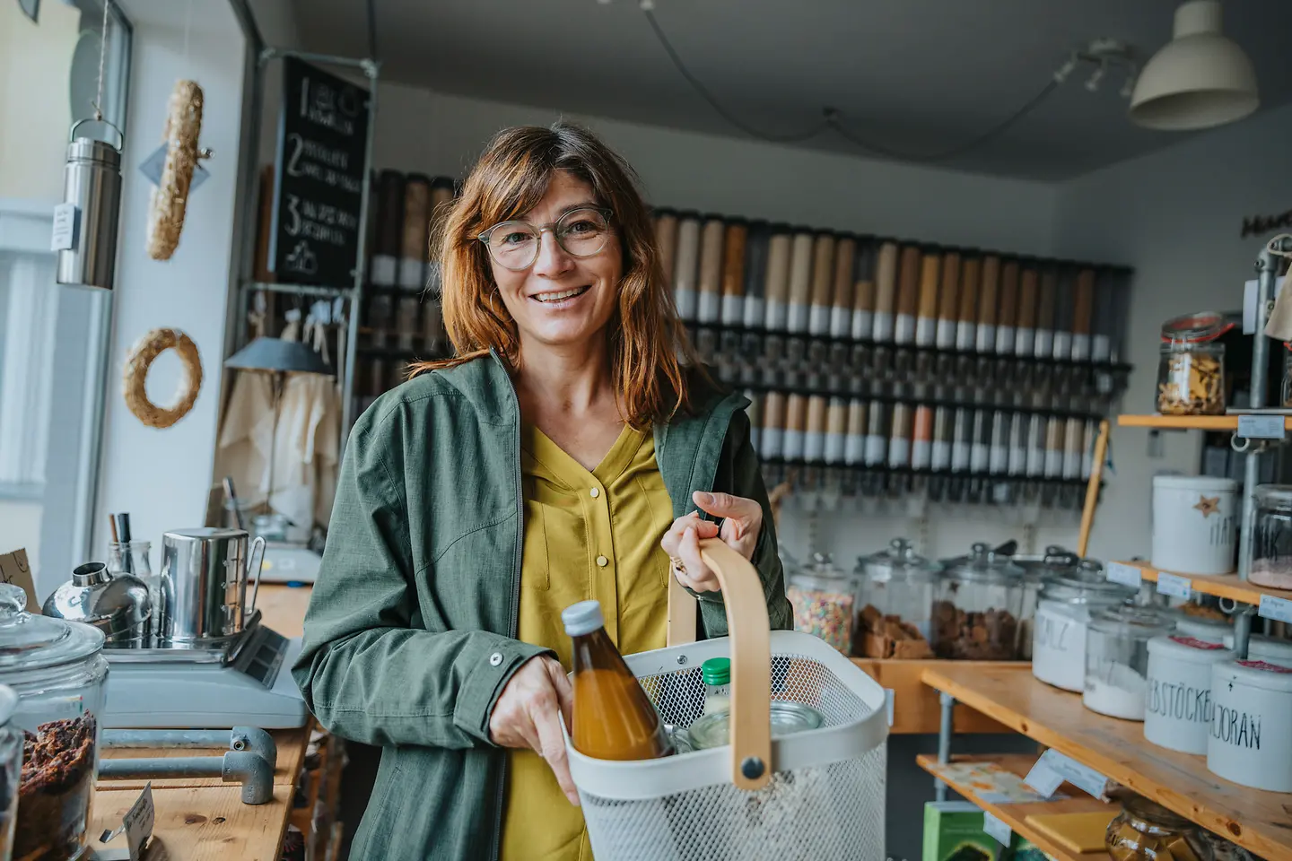 Eine Frau kauft in einem Unverpackt-Laden ein und hält ihren Einkaufskorb hoch