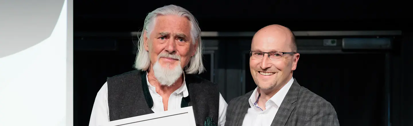 zwei Männer halten lächelnd die Urkunde "Sonderpreis der BARMER" in die Kamera