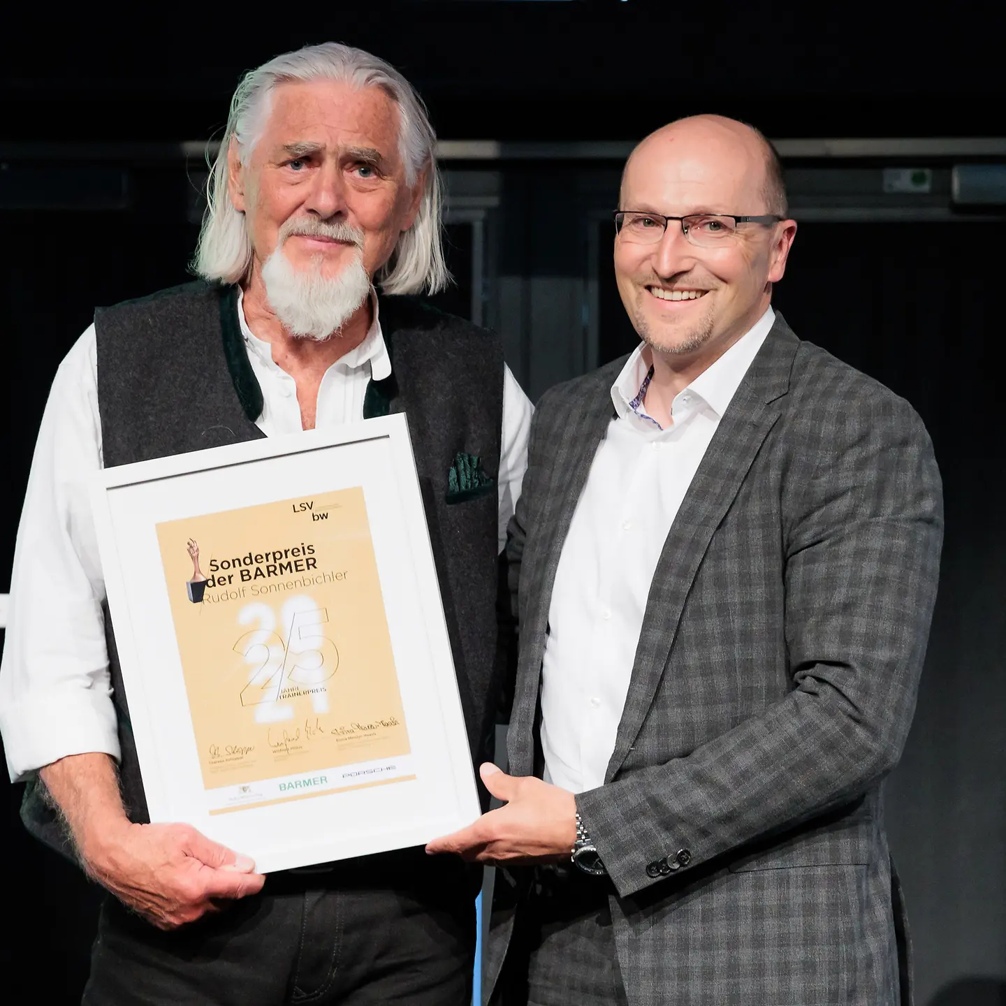 zwei Männer halten lächelnd die Urkunde "Sonderpreis der BARMER" in die Kamera