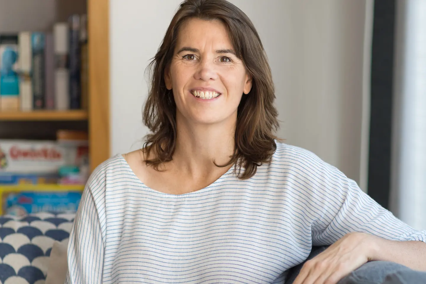 Eine Frau mit langen braunen Haaren lächelt in die Kamera