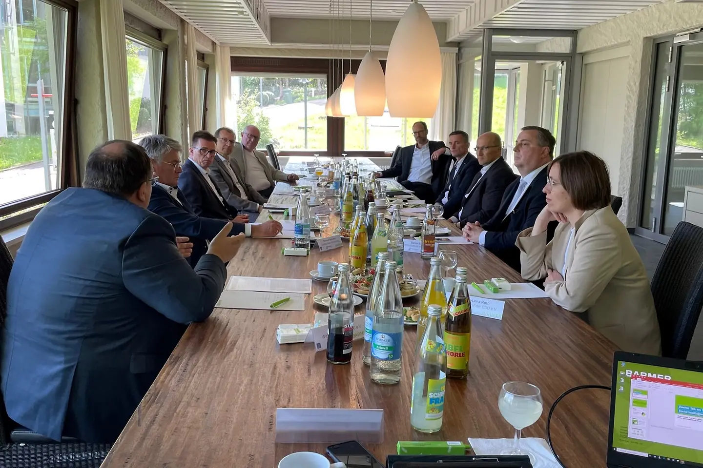 Eine Frau und neun Männer sitzen diskutierend an einem Tisch