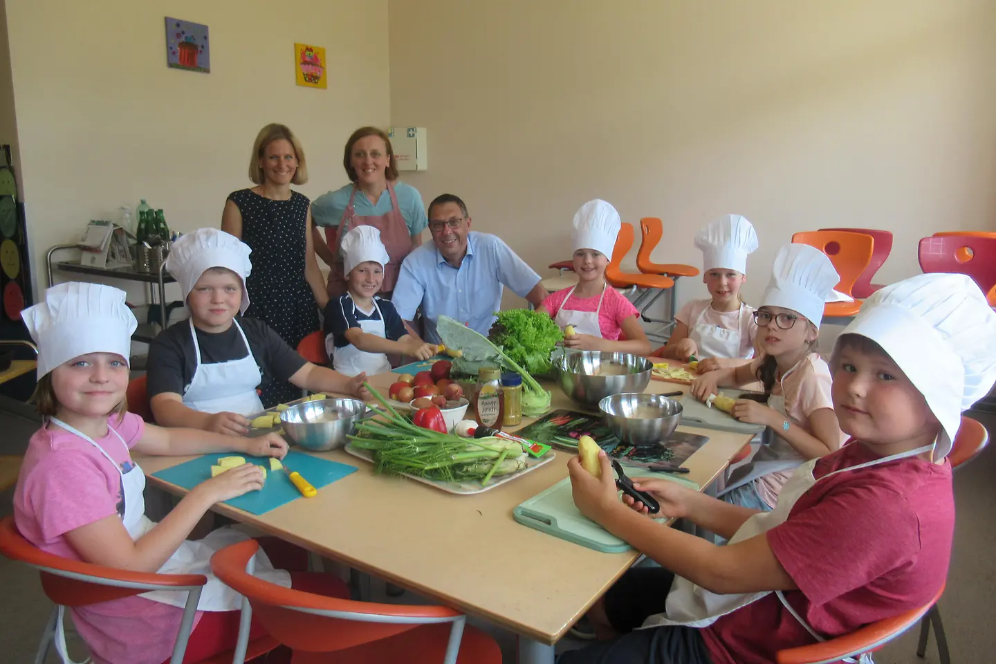 Kinder sitzen am Tisch und schneiden Gemüse