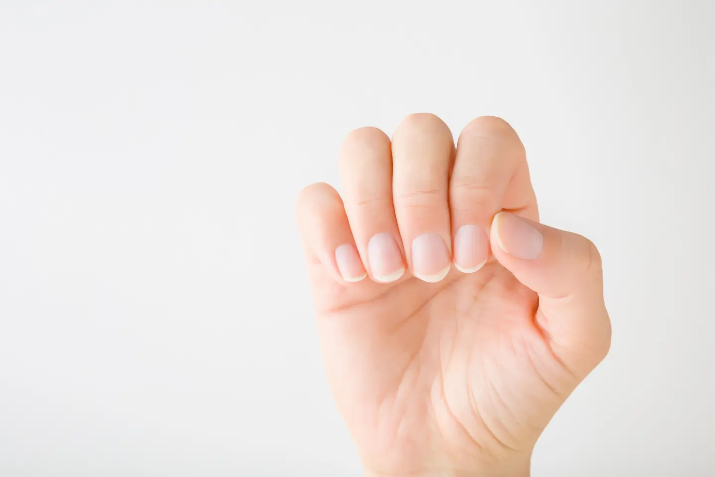 Hand mit gepflegten, natürlichen Fingernägeln