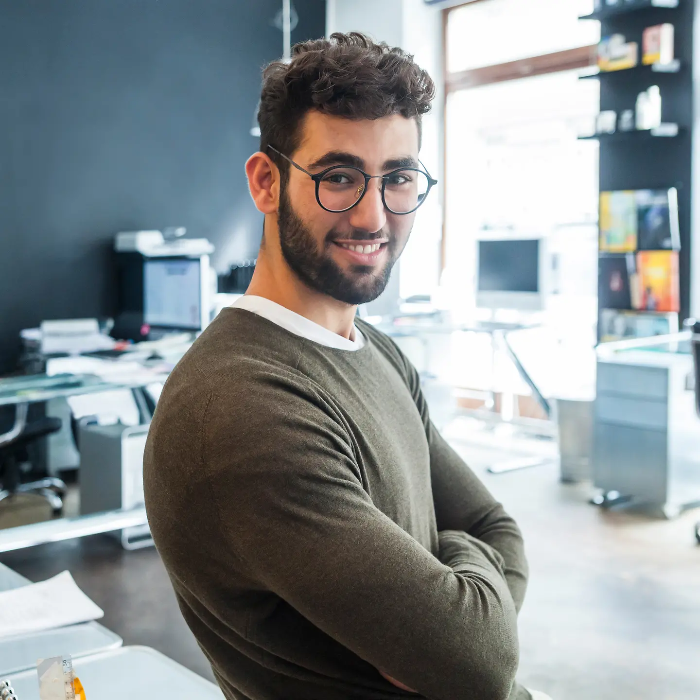 Ein junger Mann in einem modernen Büro schaut freundlich