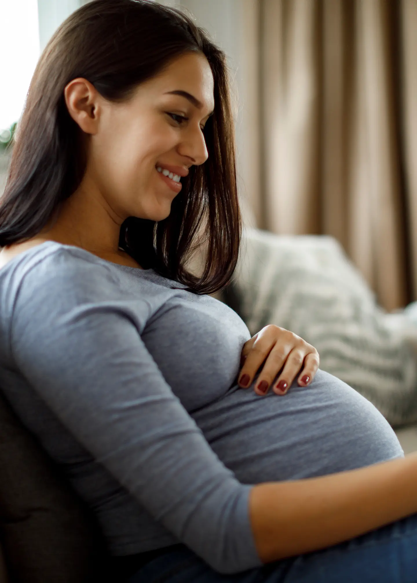 Eine schwangere Frau sitzt mit dem iPad auf dem Sofa