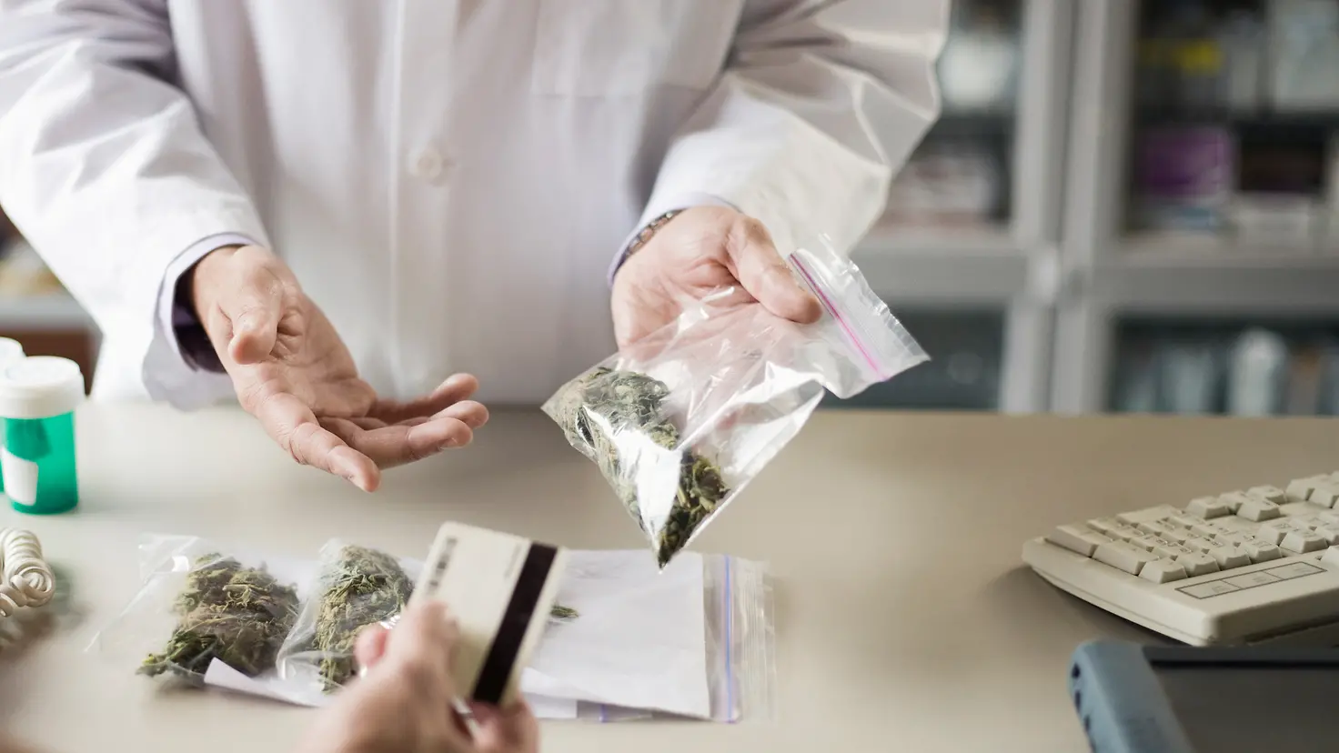 Ein Apotheker gibt einem Kunde medizinisches Cannabis auf Rezept