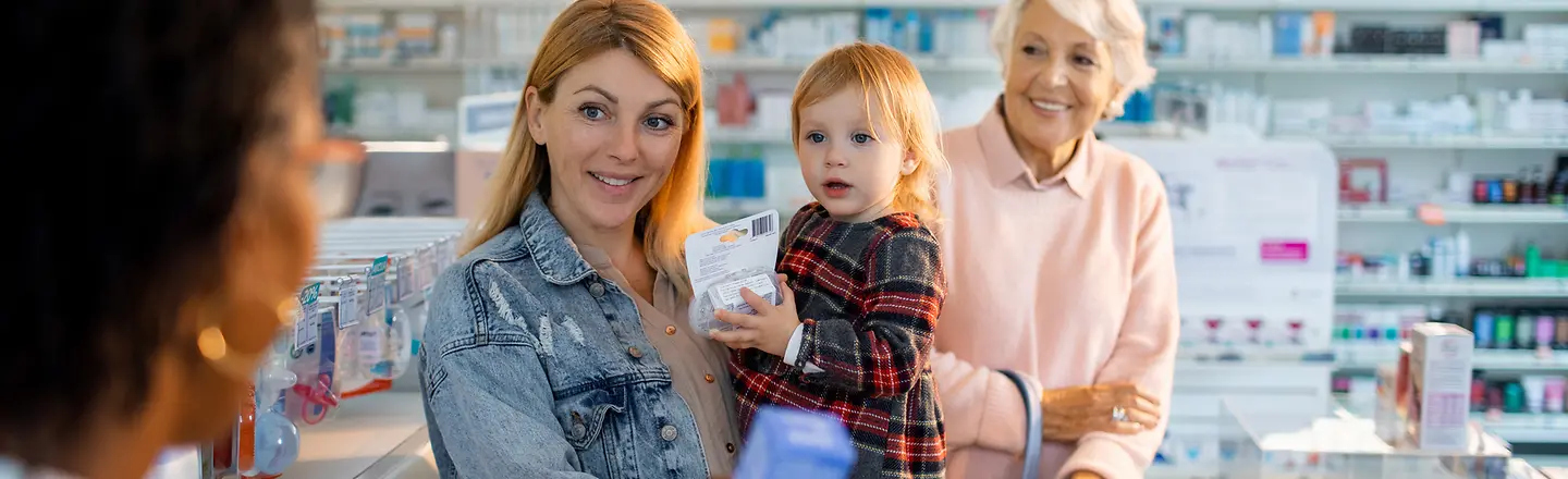 Eine Mutter mit Kind und Oma kauft in der Apotheke ein Medikament