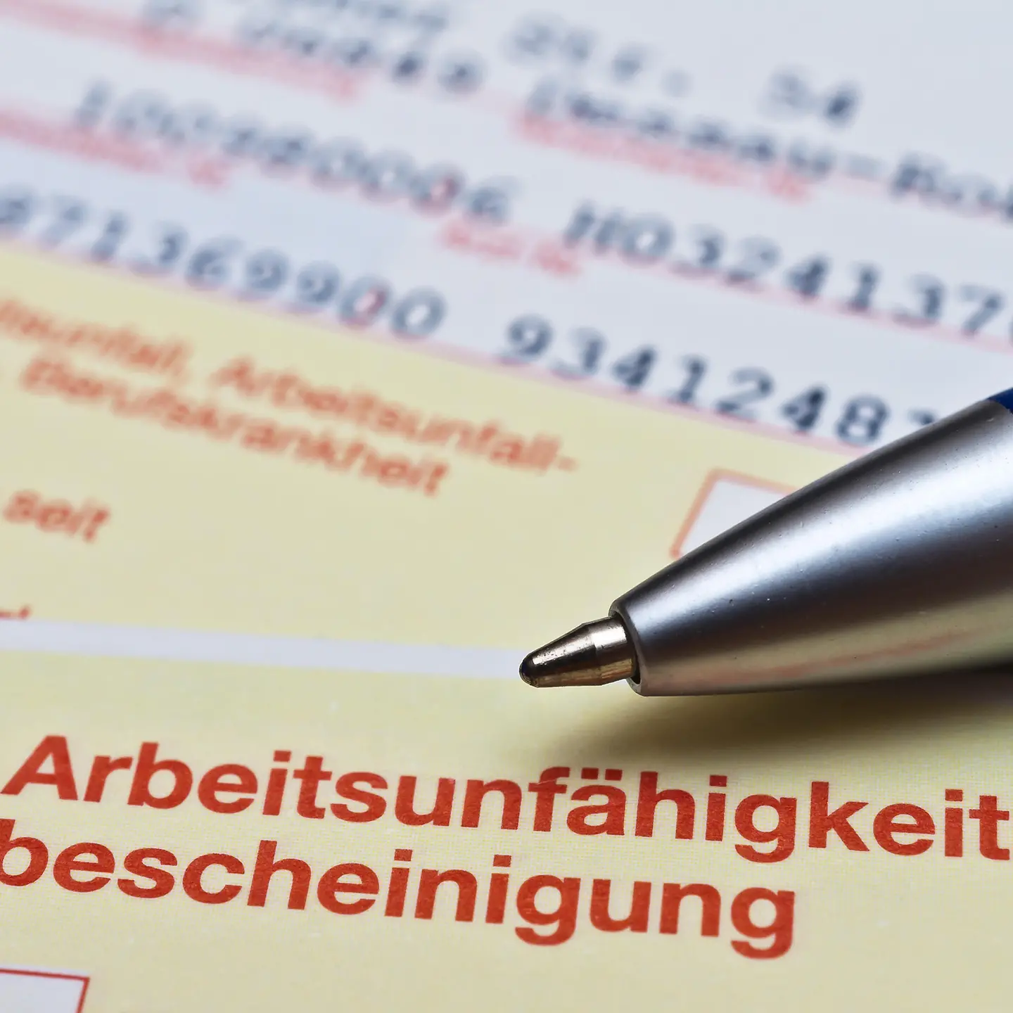 Blick auf eine Arbeitsunfähigkeitsbescheinigung (Krankschreibung) auf der ein Kugelschreiber liegt.