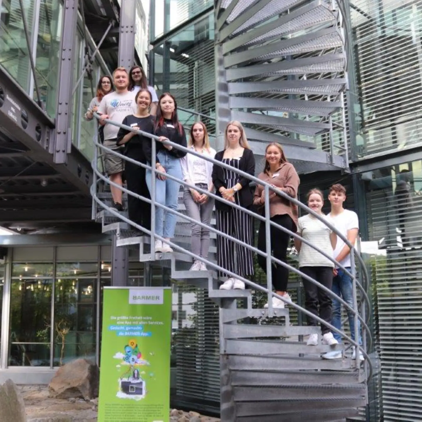 Zehn junge Frauen und Männer stehen auf einer Wendeltreppe