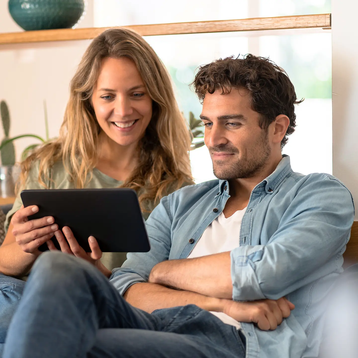 Ein Paar sitzt auf der Couch und informiert sich im Internet mit einem Tablet