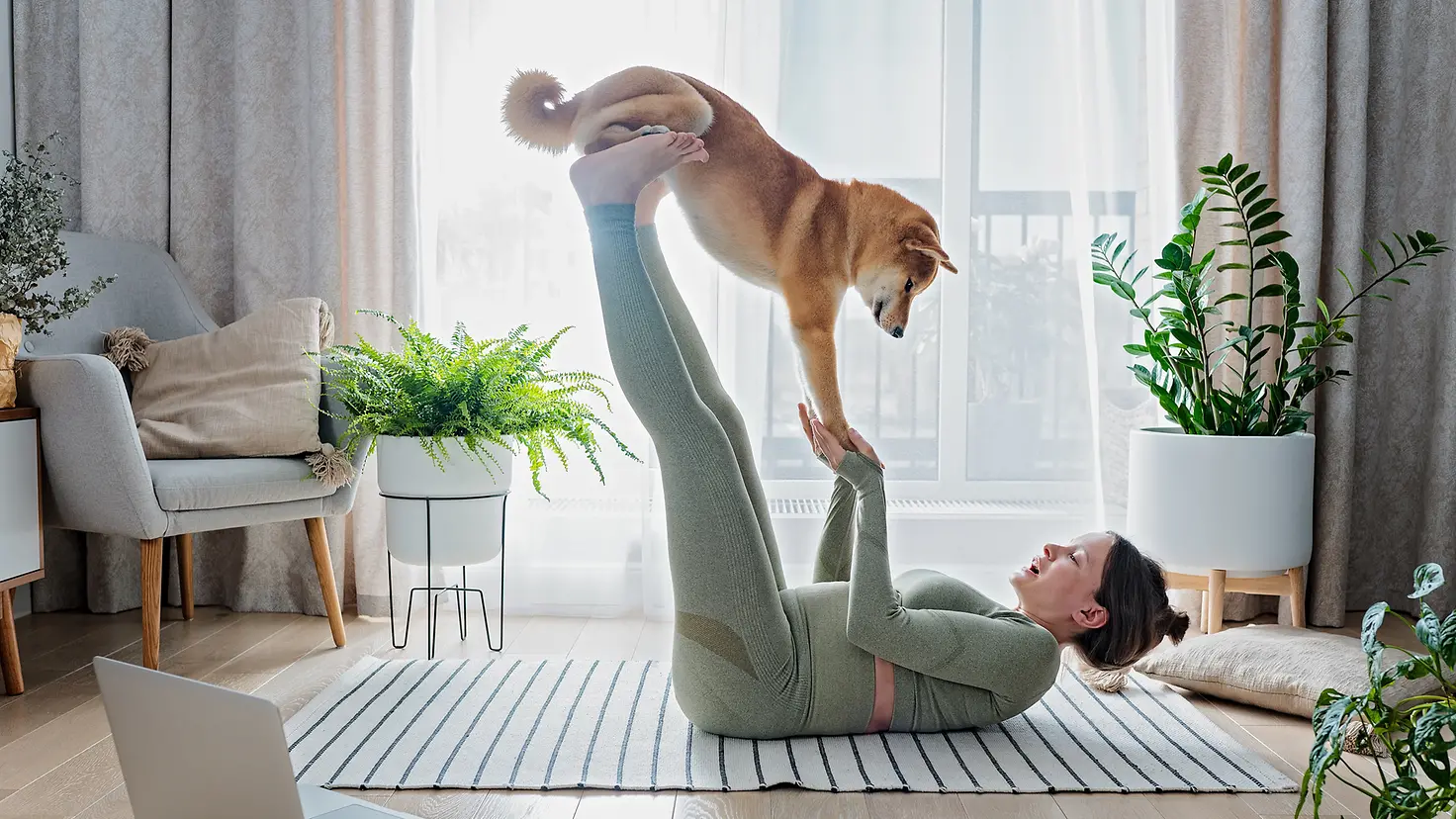 Eine Frau macht während des Intervallfastens gemeinsam mit ihrem Hund Sport zuhause
