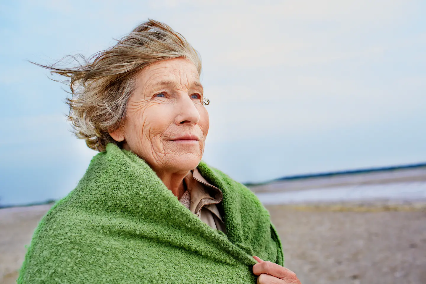 Eine ältere Frau geht am Strand spazieren