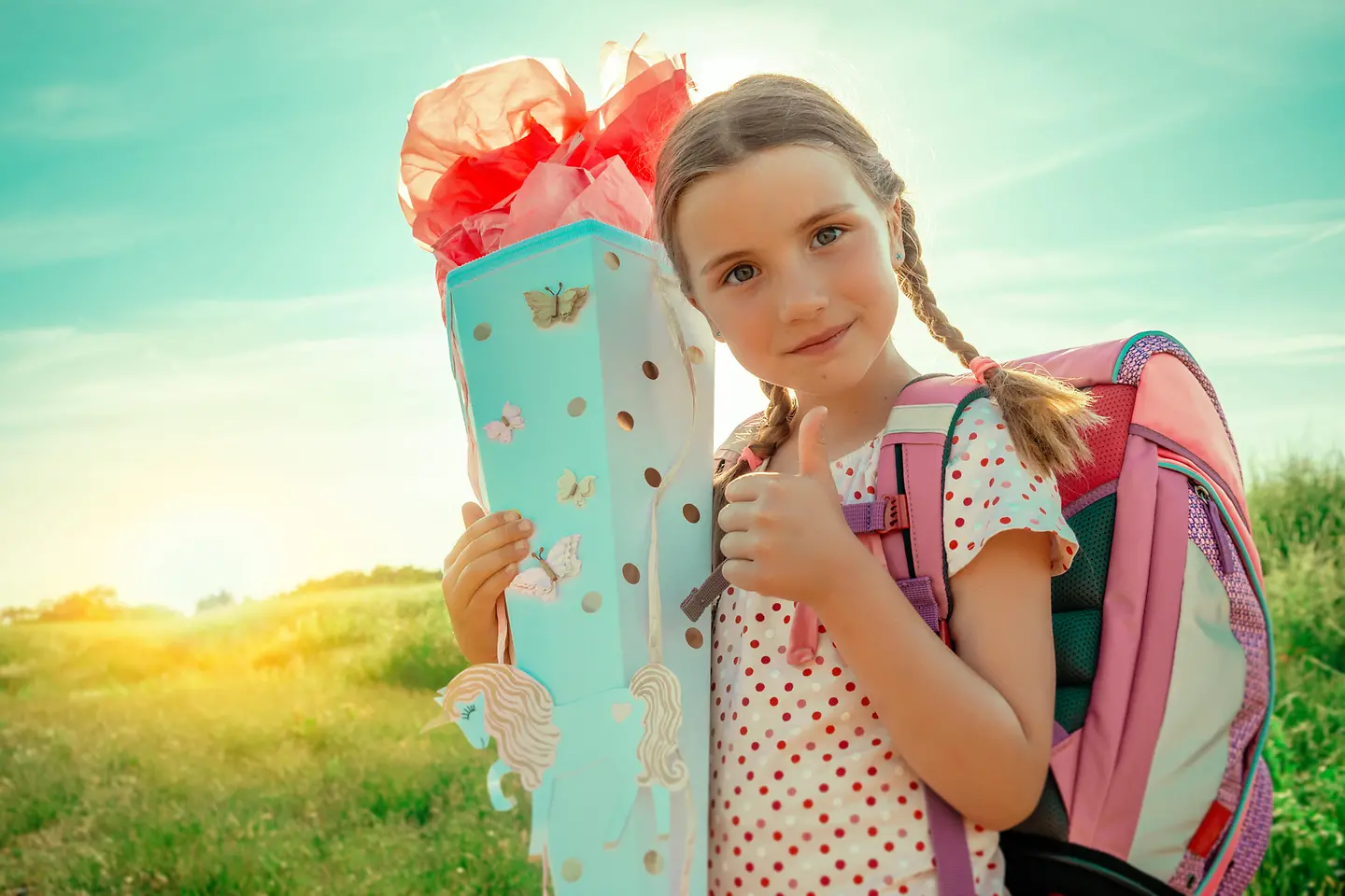 Ein Mädchen hält eine Schultüte in der Hand und zeigt mit der anderen Hand ein "Daumen hoch"