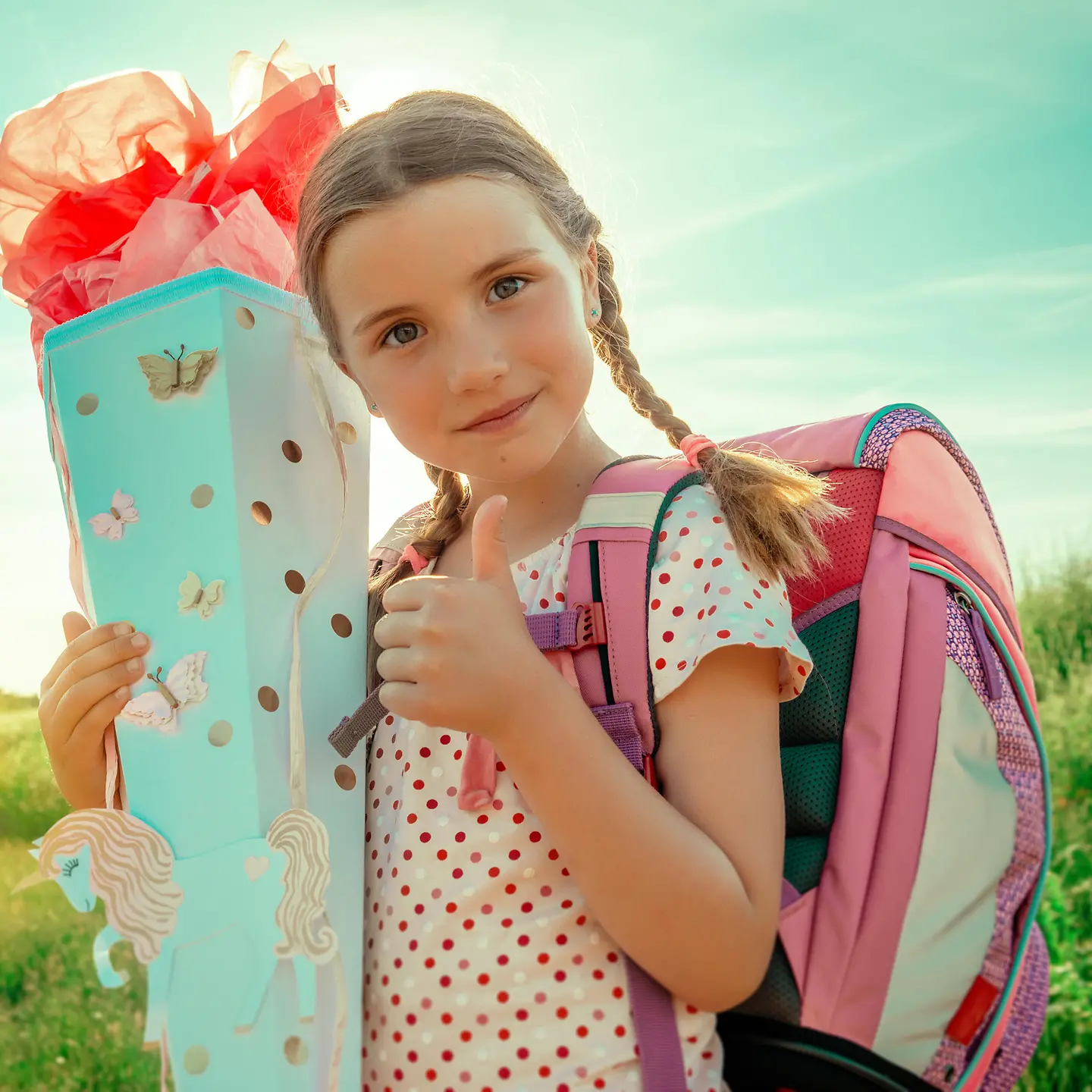 Ein Mädchen hält eine Schultüte in der Hand und zeigt mit der anderen Hand ein "Daumen hoch"
