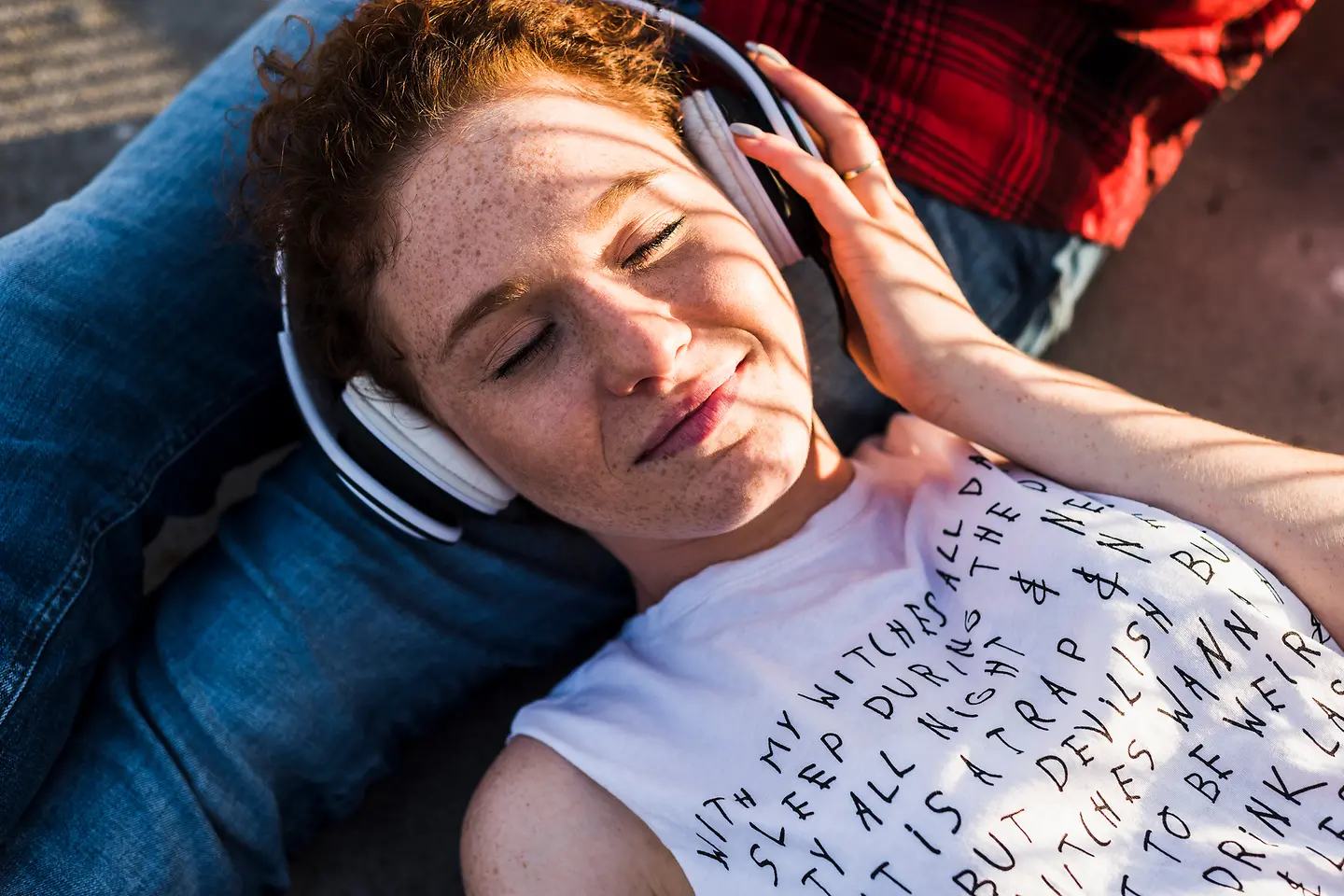 Eine Frau liegt mit Kopfhörern auf dem Boden und testet die Wirkung von binauralen Beats.