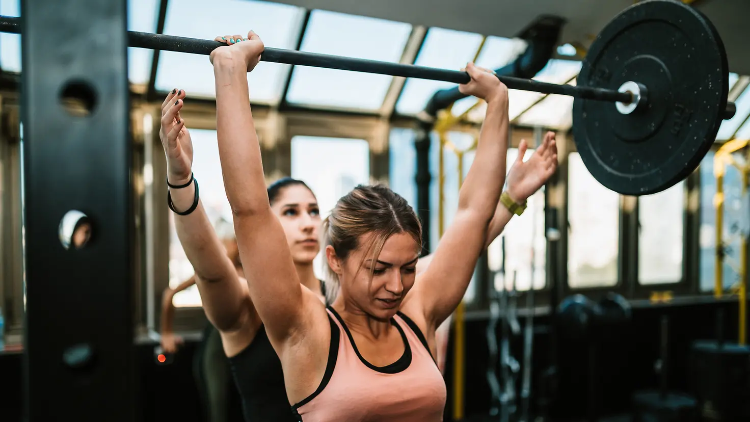 Eine junge Frau macht Hanteltraining und trainiert ihre Muskeln.