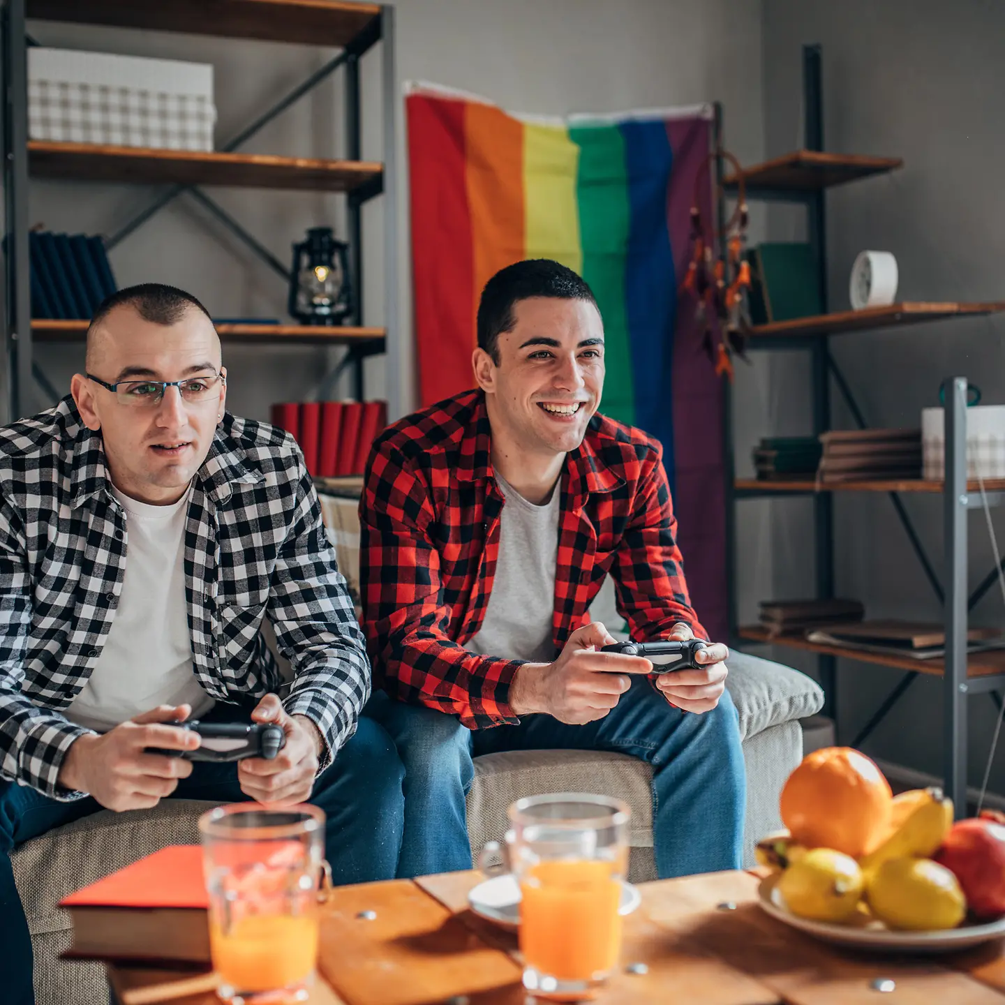 Zwei Männer spielen ein Computerspiel und essen dabei Obst.