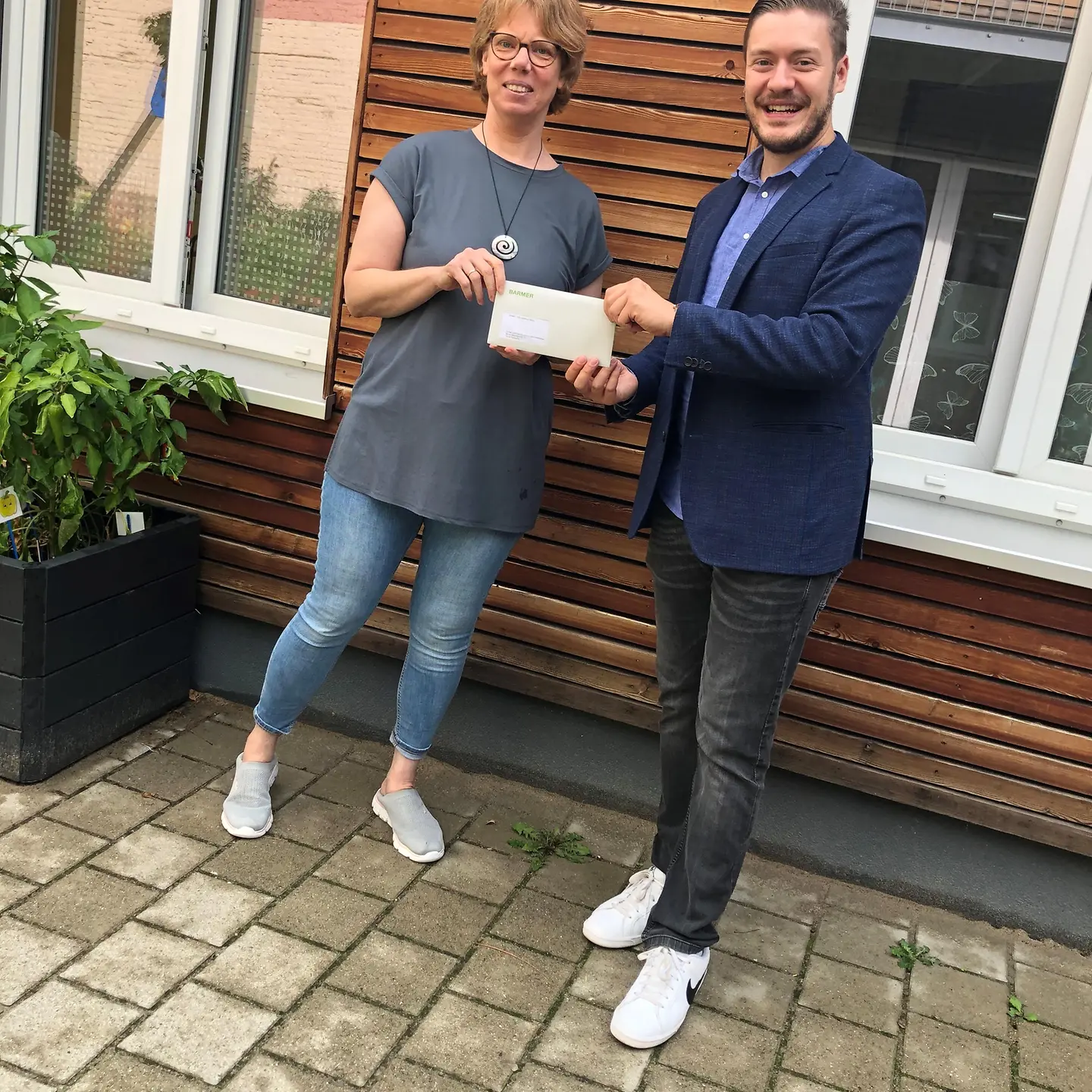 Ein Mann und eine Frau halten gemeinsam einen Brief in die Kamera