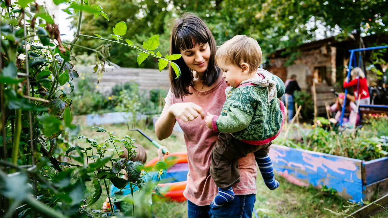 Mutter mit Kleinkind auf dem Arm im Garten 