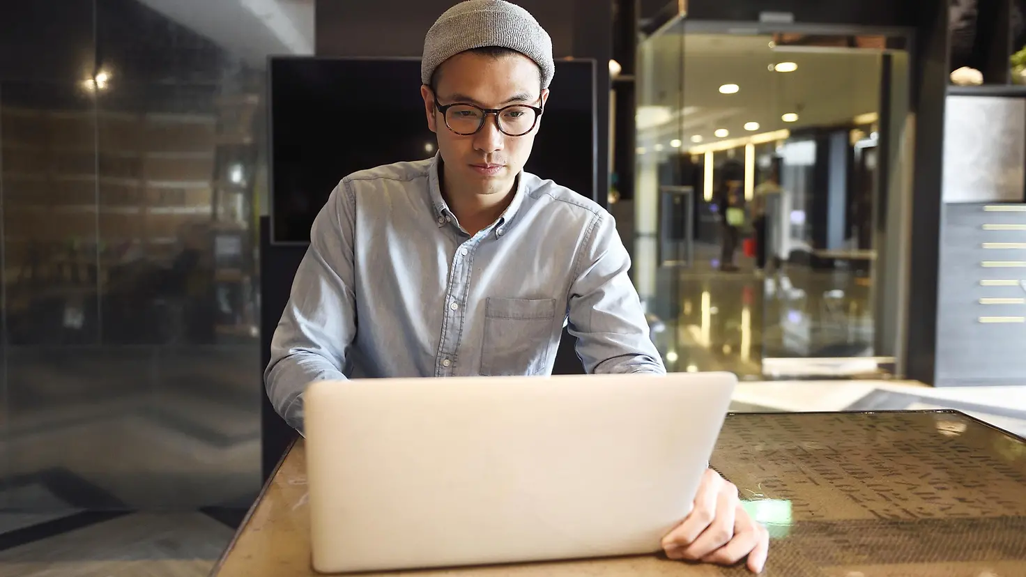 Junger Mann sitzt in modernem Büro am Laptop