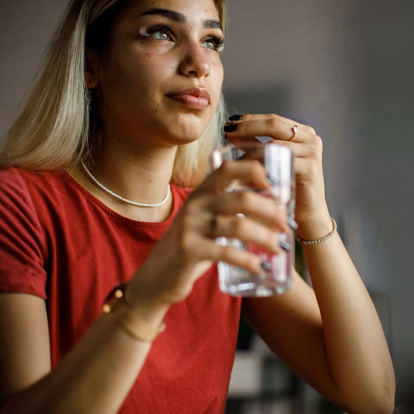 Junge Frau nimmt ein Medikament mit einem Glas Wasser ein