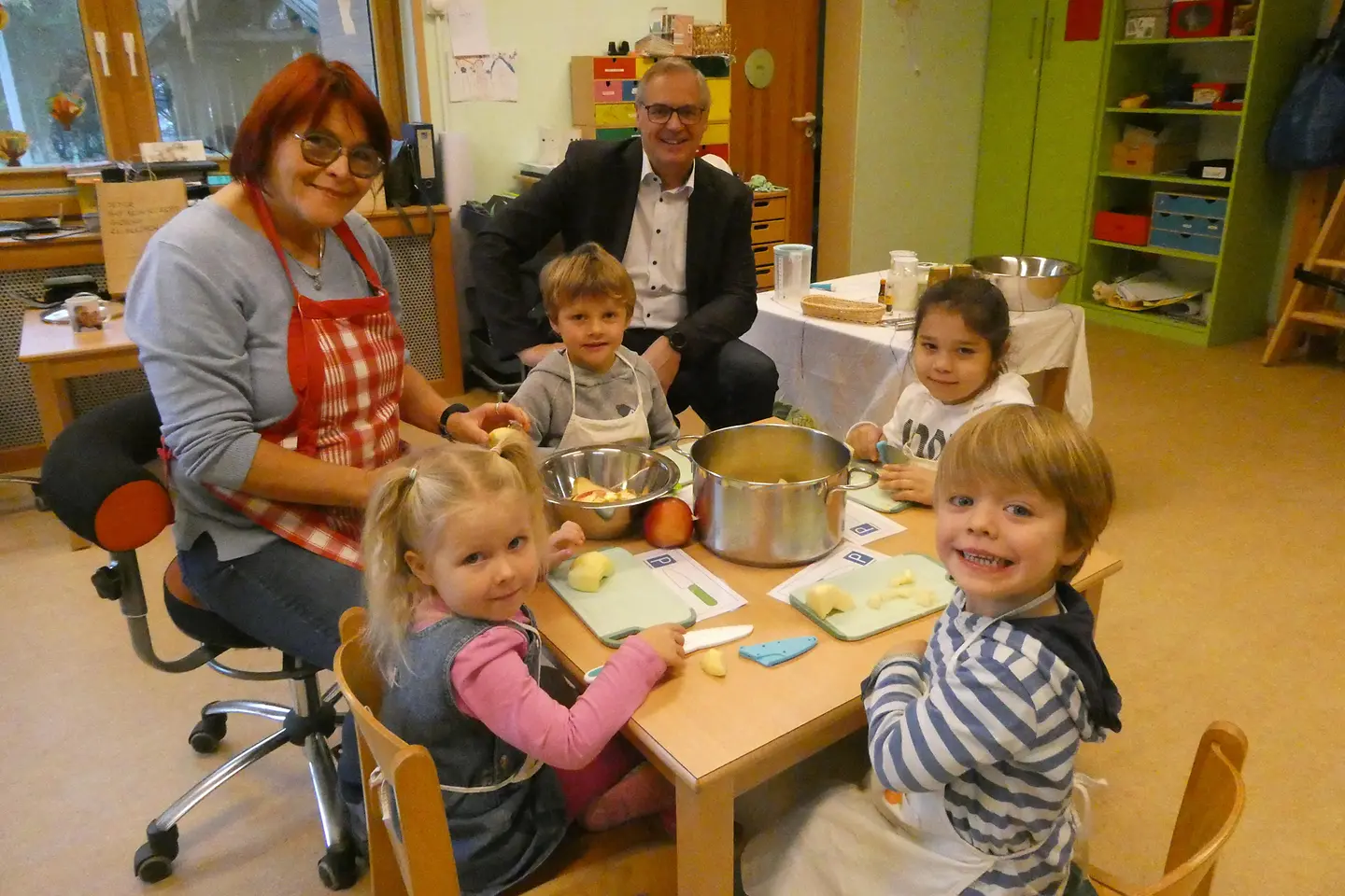 Kinder sitzen am Tisch und schnippeln Äpfel