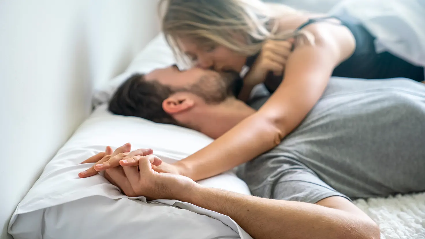 Ein junges Paar liegt im Bett und küsst sich zärtlich