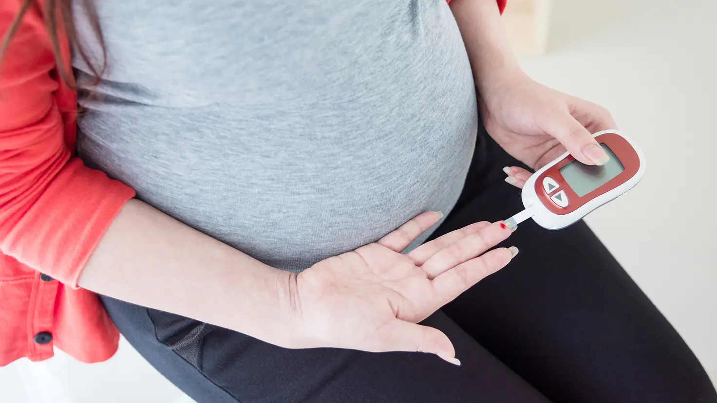Eine schwangere Frau misst ihren Blutzuckerspiegel.