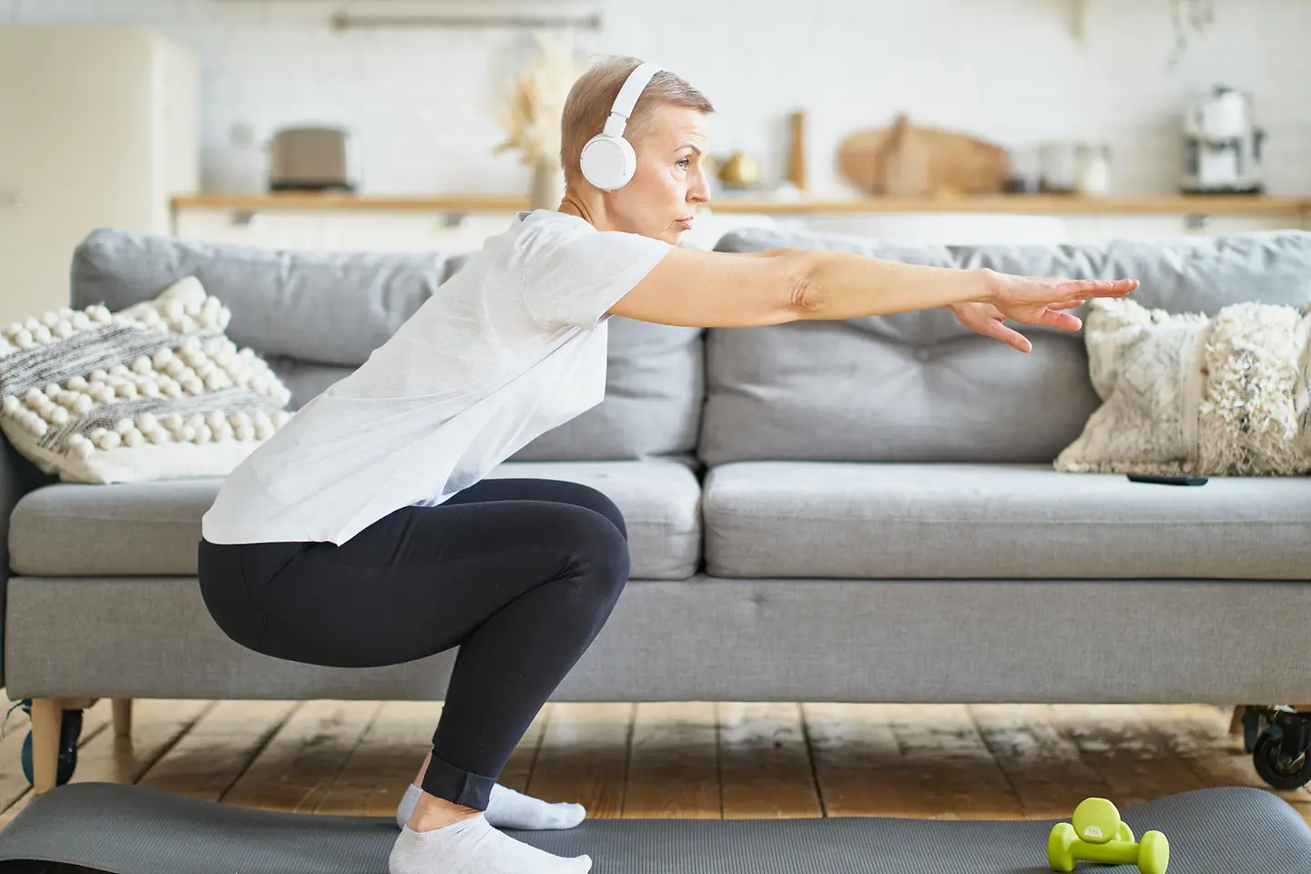 Eine Frau führt in ihrem Wohnzimmer Gymnastikübungen zur Vorbereitung auf den Wintersport aus.
