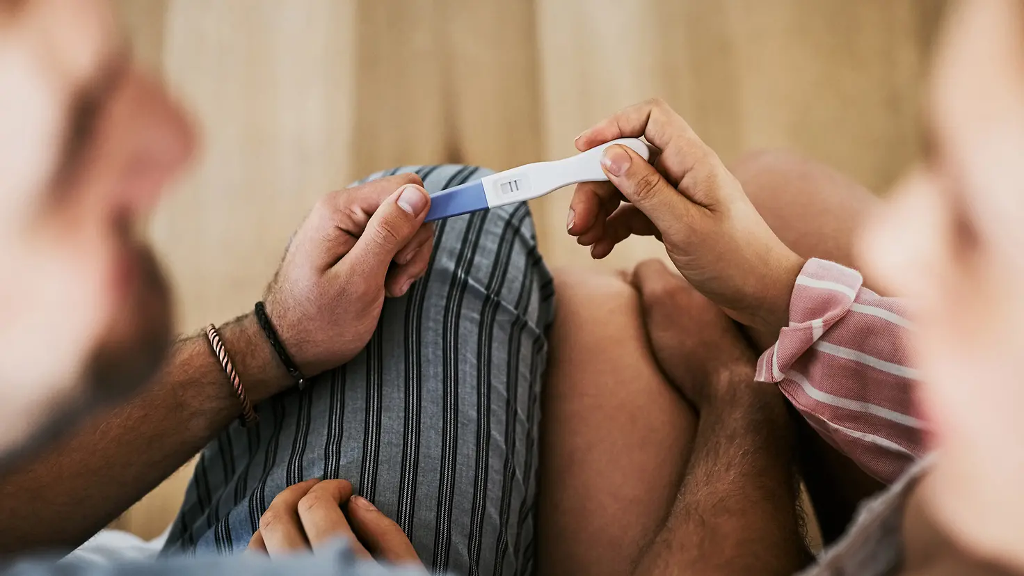 Ein Paar hält zusammen einen positiven Schwangerschaftstest.