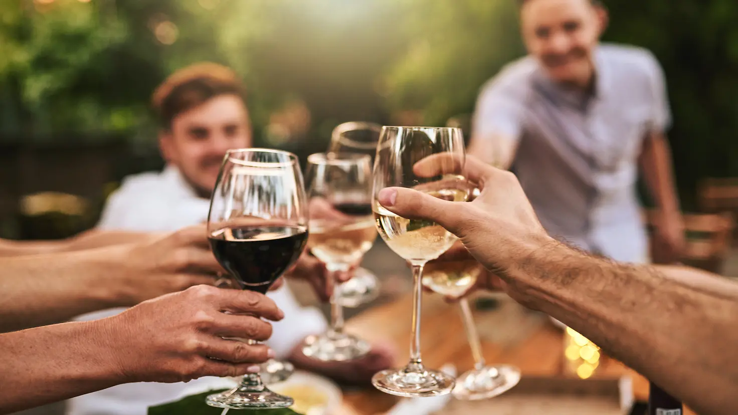 Alkohol? Besser nicht nach der Impfung: Eine Gruppe von jungen Menschen stößt mit einem Glas Wein an.