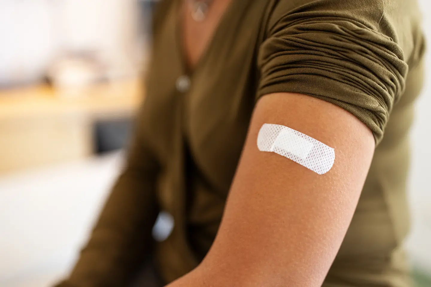 Der Arm einer Frau mit einem Pflaster auf der Einstichstelle der zuvor verabreichten Diphtherie-Impfung. 