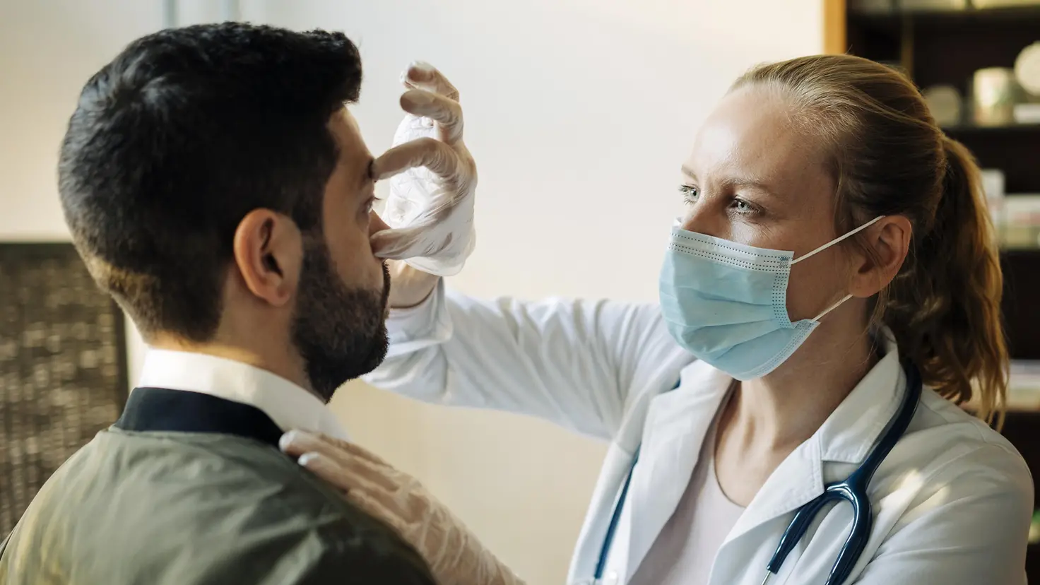 Eine junge Ärztin untersucht im Rahmen des Check-ups die Augen eines Patienten