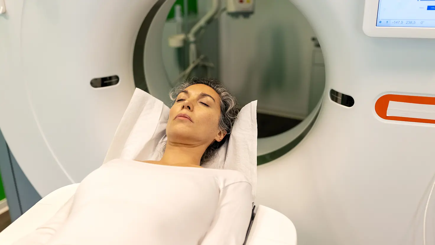 Eine Frau auf einer Therapieliege, hinter ihr befindet sich ein Tomotherapiegerät für die Strahlenbehandlung bei Leukämie.