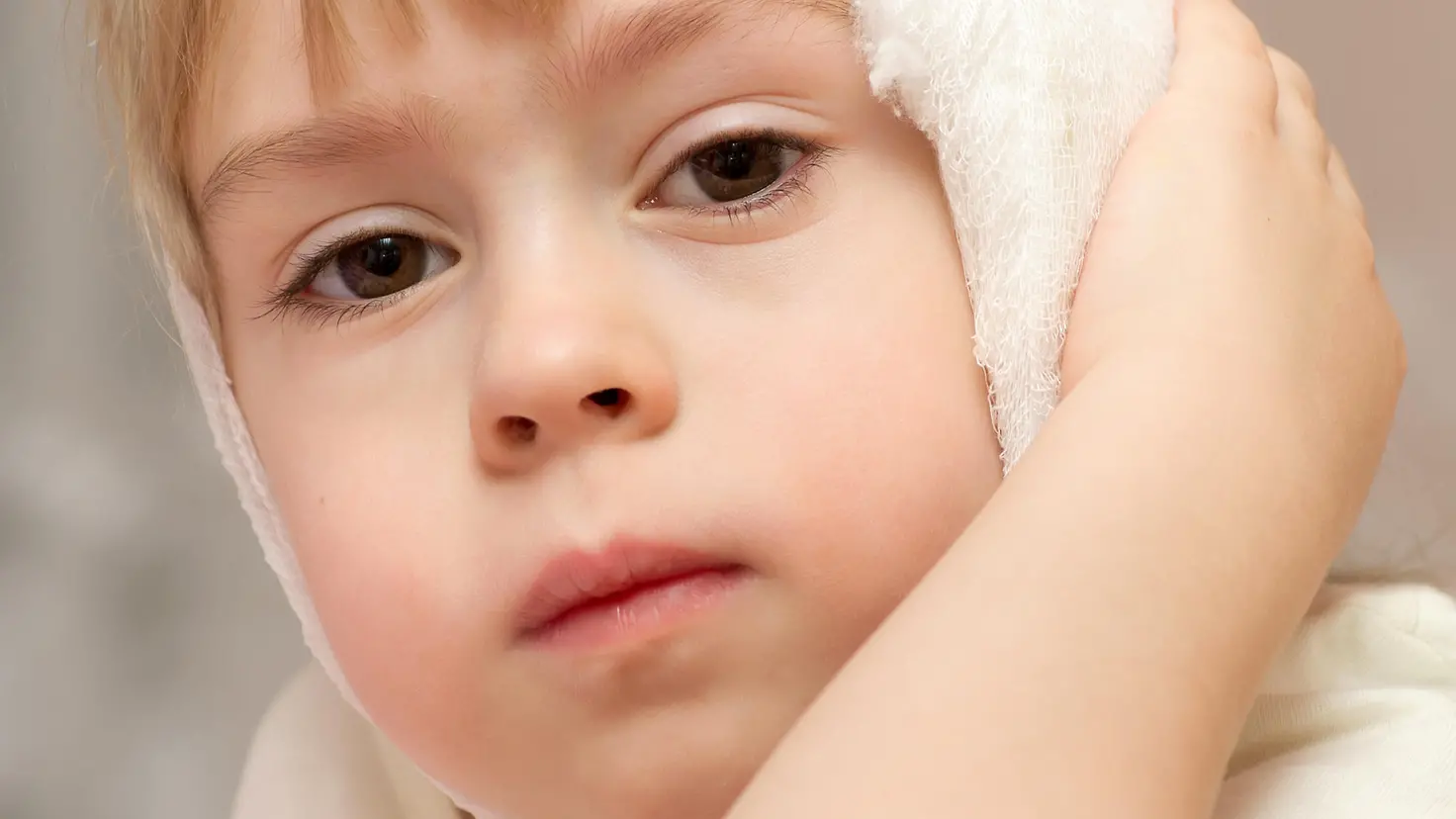 Zu sehen ist ein Kind mit einem Verband am Ohr
