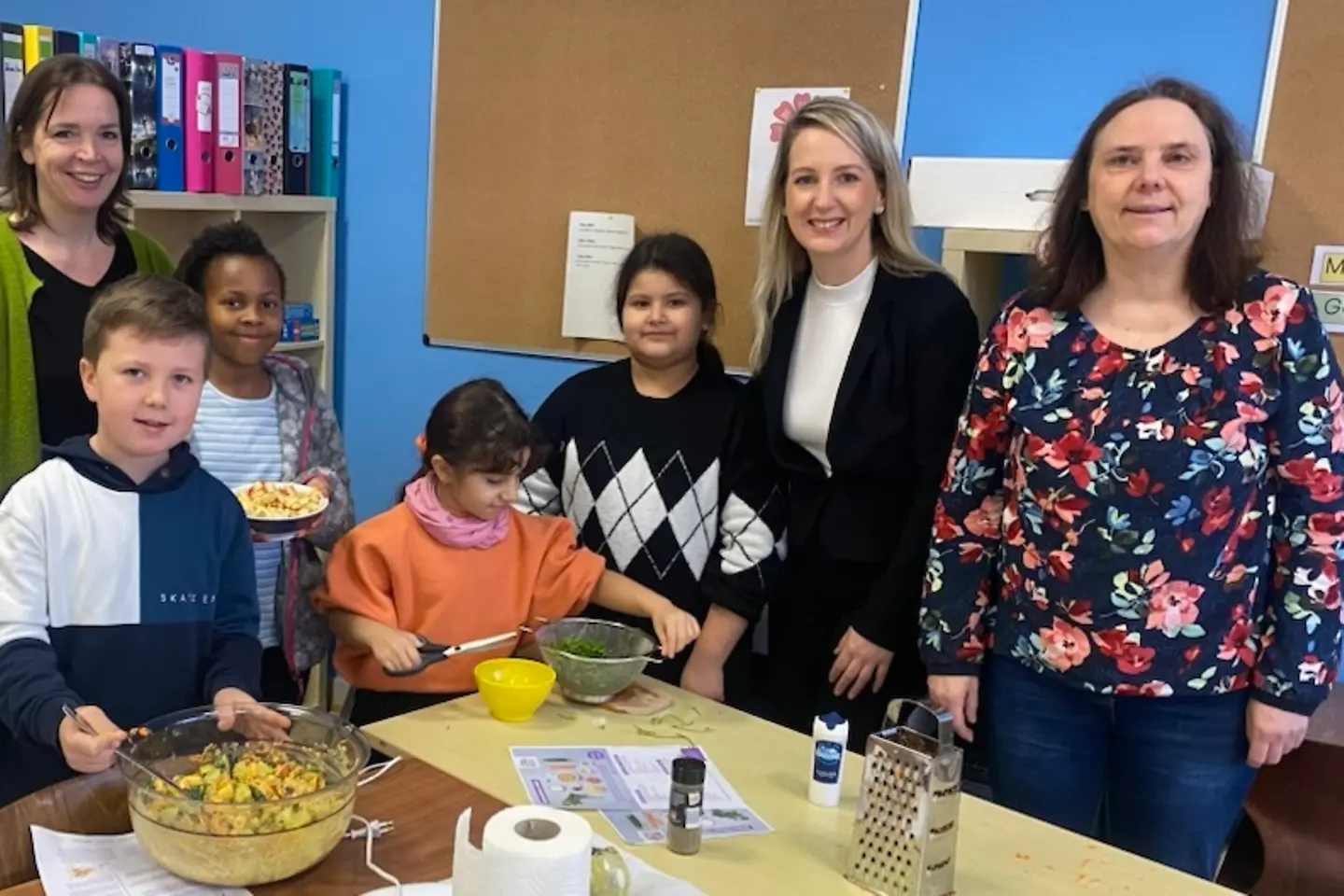 Kinder zeigen zubereitete Lebensmittel, zwei Lehrerinnen und eine BARMER-Vertreterin stehen dabei