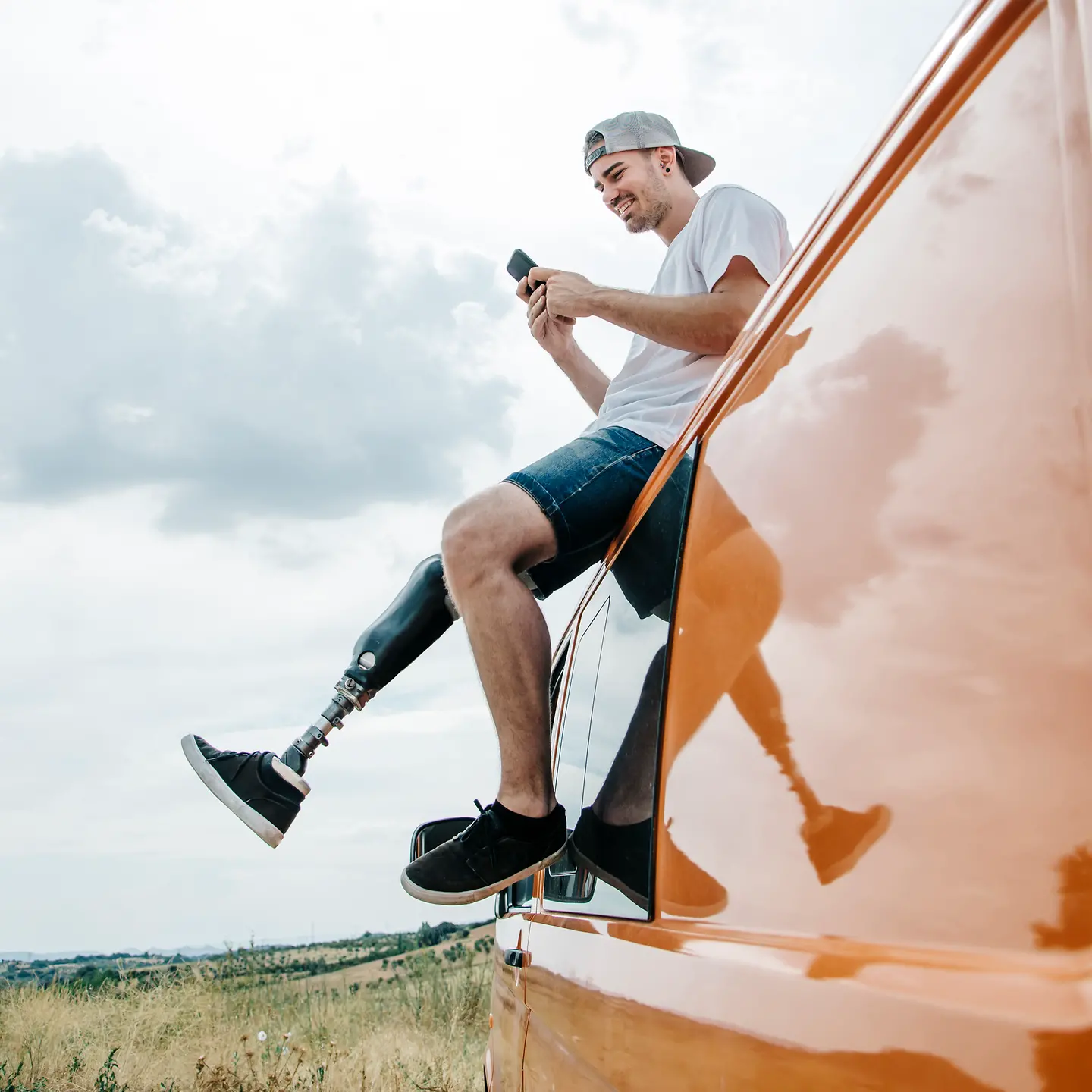 Ein junger Mann mit Beinprothesen auf dem Autodach