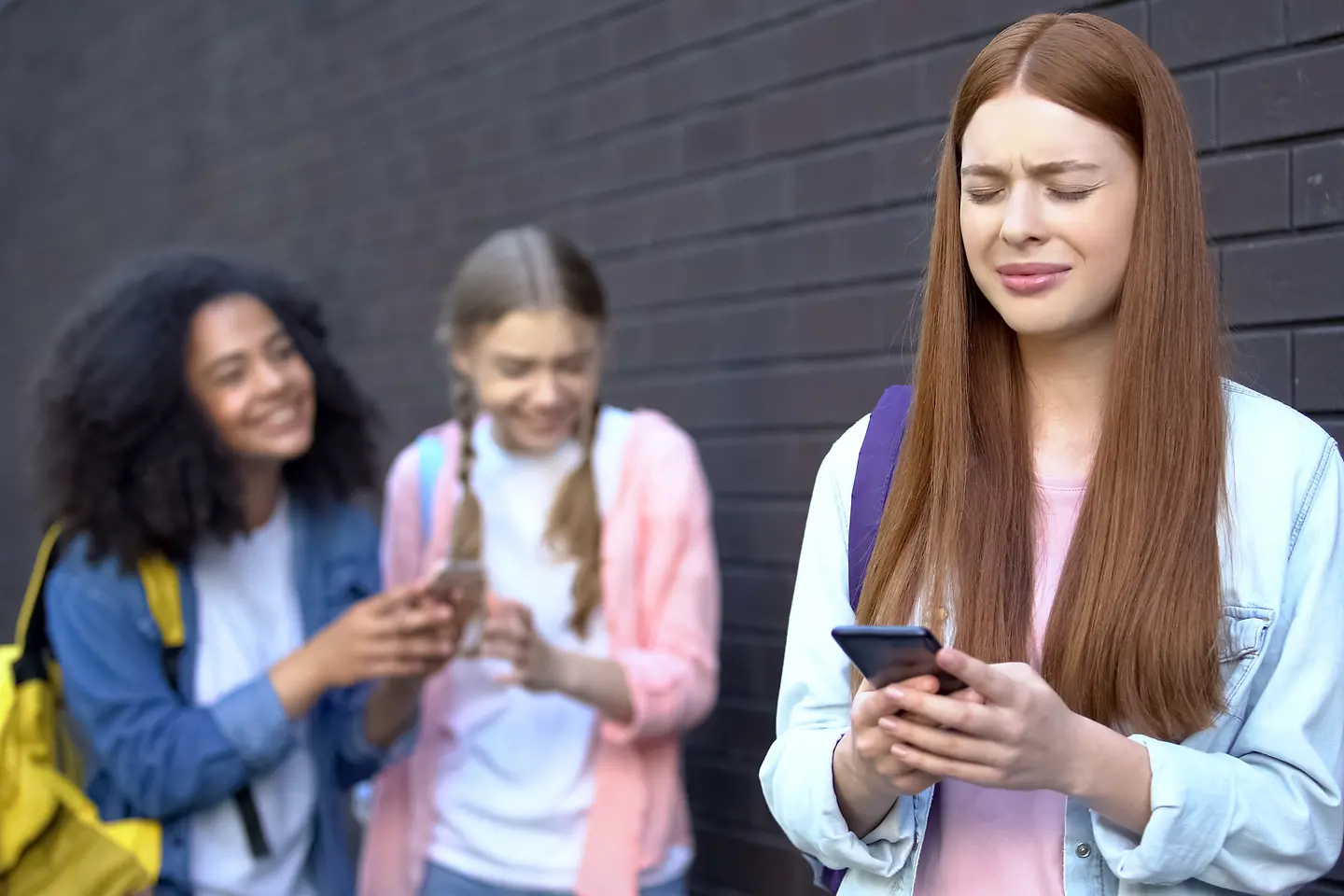 Zu sehen ist ein ängstliches Mädchen mit Smartphone
